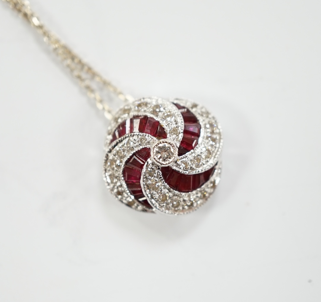 A modern 18ct white gold, ruby and diamond cluster set pendant, 14mm, on a 750 white metal fine link chain, 39cm, gross weight 3.4 grams.